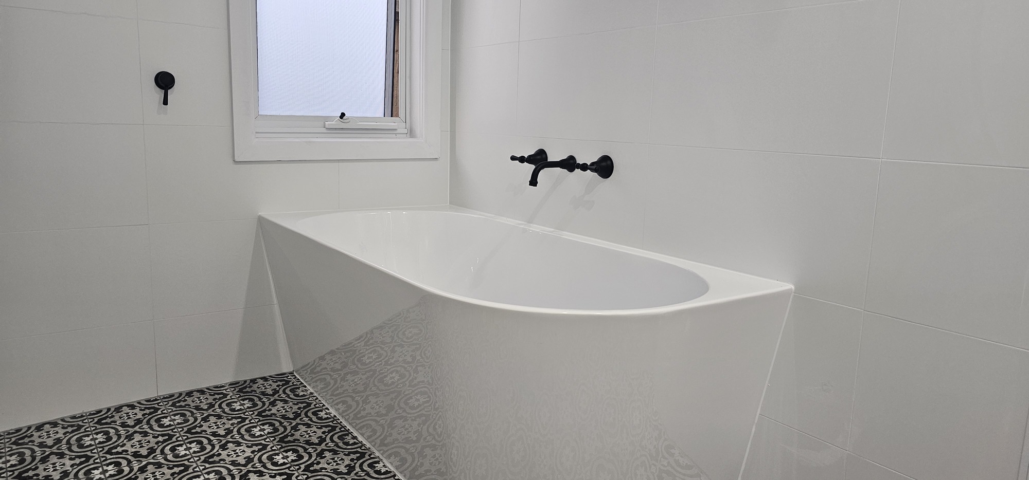 VZ bathroom renovation with a freestanding bath, white wall tiles and patterned floor tiles